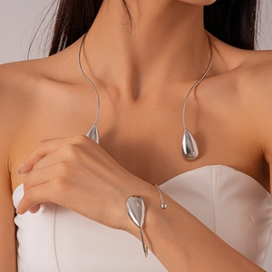 Gros plan d'un collier ras-du-cou et bracelet argentés minimalistes avec gouttes d'eau