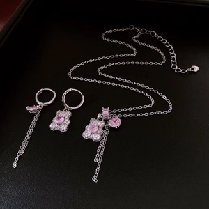 Macro shot of bear jewelry set with pink heart gems and tassels on black leather
