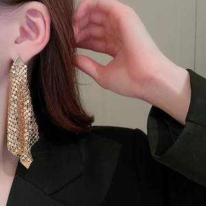 Gros plan de boucles d'oreilles dorées à franges triangulaires sur un mannequin élégant