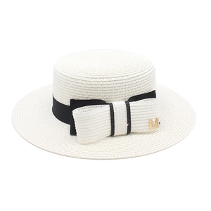 Detailed view of white flat-top boater hat featuring a black ribbon and gold M letter metal charm