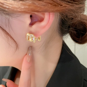 Elegant gold M-shaped letter earrings with zircon stones shown on ear model