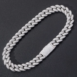 Macro shot of 20mm Cuban link chain with pavé-set zircons on dark leather surface