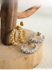 Gros plan de boucles d'oreilles créoles dorées et argentées avec perles et zircons