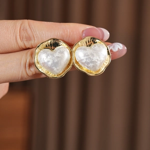 Détail des boucles d'oreilles cœur plaquées or 16K avec métal plissé et perle nacrée