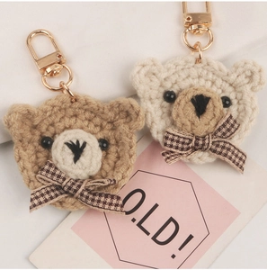 Close-up of handmade crochet bear keychains with plaid bows and golden lobster clasps