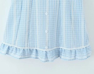 Detail of light blue plaid dress featuring lace patchwork, white buttons and ruffle hem