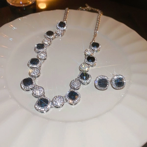 Detailed view of silver necklace and earrings set with black square gems and diamonds