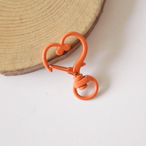 Macro shot of bright orange heart-shaped lobster clasp on natural wood display