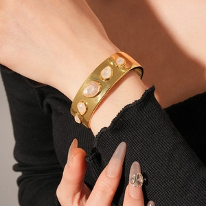 Gros plan d'un bracelet doré en résine avec gouttes d'eau et pierres sur un poignet