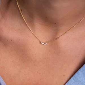 Detail of gold snake necklace with 5 zirconia stones and pearls worn by a model
