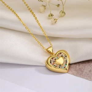 Macro detail of a gold heart pendant with colorful zircon stones on white silk fabric