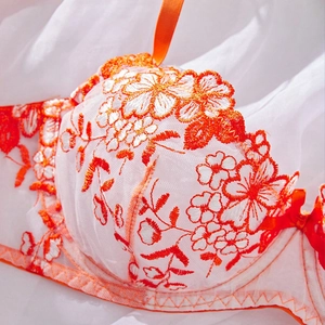 Close-up of intricate orange floral embroidery on white sheer lace bra cup detail