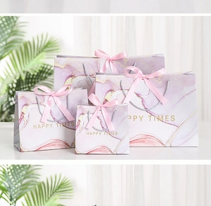 Detail of pink marble gift bags with satin ribbon handles and golden Happy Times text