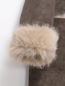 Détail d'un manteau en daim marron avec garniture en fausse fourrure beige sur les poignets
