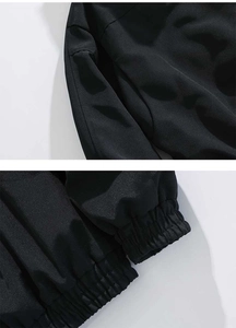 Detail van het windjack met focus op de stoftextuur en de elastische geribbelde manchetten