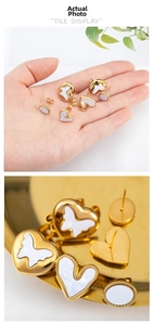 Detail of gold earrings set with heart and butterfly shapes and white enamel inlays