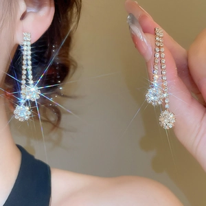 Close-up of sparkling flower tassel earrings with zircons and gold plating on a model