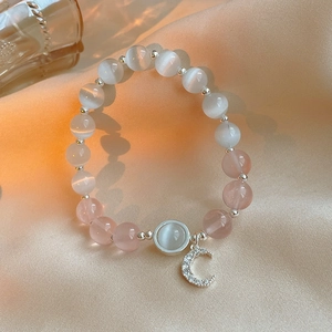 Detailed shot of moon pendant on cat-eye stone bracelet with silk background