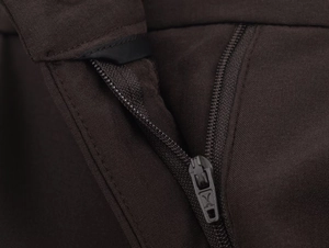 Gros plan du tissu marron foncé et de la fermeture éclair métallique du pantalon