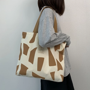 Detail of canvas tote bag with brown abstract print and Good Student label on shoulder