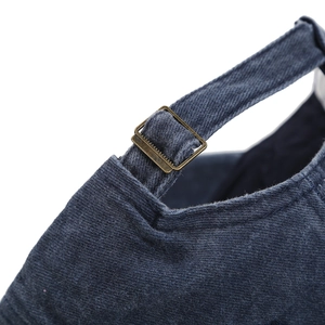 Detail of adjustable brass buckle and textured navy cotton twill on the back of baseball cap