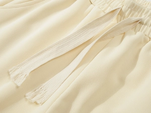 Macro view of cream knit athletic shorts showing elastic waist and woven drawstring