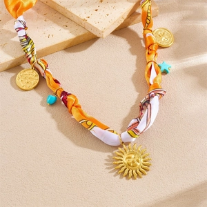 Detail of silk scarf necklace with golden sun face and colorful heart charms on stone