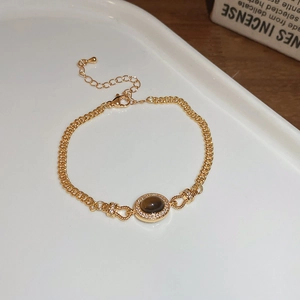 Détail d'un bracelet vintage doré avec pierre brune et cristaux blancs brillants