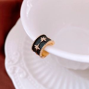 Detail of star pattern black enamel ear cuff with white zircons on a white cup