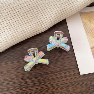 Detail shot of mini iridescent bow hair clips with laser polar effect on wood surface