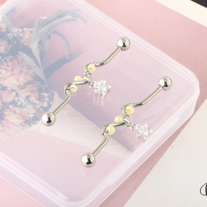Detail of silver wavy industrial barbell with cream pearls and a crystal star charm