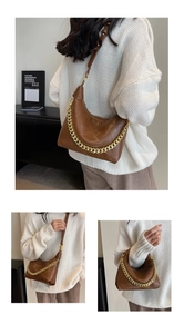 Three-way view of brown leather bag with gold chain strap and geometric fold design