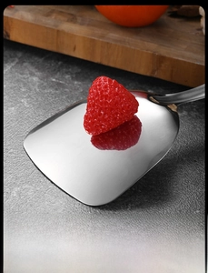 Macro shot of mirror-polished stainless steel spatula with clear strawberry reflection