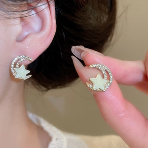 Detailed close-up of star and moon earrings with gold setting and sparkling crystals