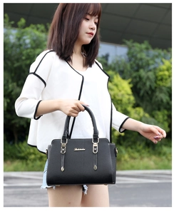 Outdoor model display of a black PU leather handbag with dual handles and metal hardware