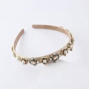 Detailed view of beige fabric headband with vintage gold flower gems and pearls