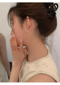 Close-up of a model wearing a gold hollow flower hoop earring made of S925 silver