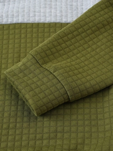 Detailed macro view of olive green waffle knit texture and grey contrast cuff on hoodie