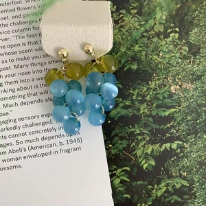 Detail von traubenförmigen Ohrringen mit blauen und grünen Harzperlen auf Goldhaken
