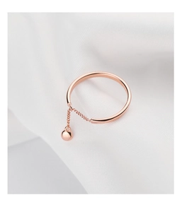 Detail of rose gold open ring featuring a delicate chain and polished ball pendant charm