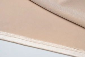 Gros plan détaillé sur les coutures fines et le tissu texturé de la robe dos nu beige