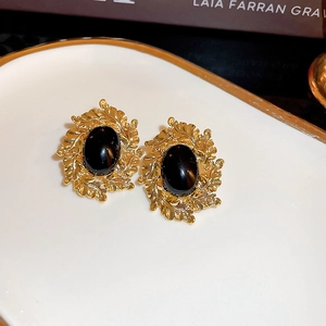 Close-up of vintage golden leaf earrings with an oval black gemstone center