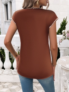 Rear view of brown short sleeve sweater with white contrast stitching on a balcony