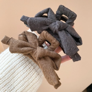 Close-up of elegant fabric bow hair claw clips in brown and dark grey tweed texture