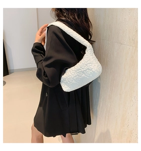 Detail of white cloud bag featuring 3D floral quilted texture and wide shoulder strap