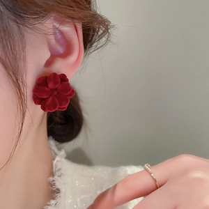 Close-up of a French vintage dark red flocked flower earring worn by a model