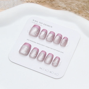 Macro view of purple French leaf press-on nails with metallic pink tips on a display card