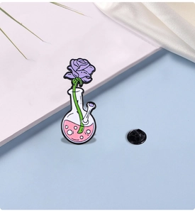 Detail of enamel pin featuring a purple rose in a flask with pink liquid and back clasp