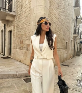 Detail of white sleeveless suit vest and wide leg trousers on European cobblestone street