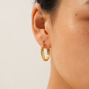 Close-up of 18k gold plated stainless steel twisted C-shape hoop earring on ear